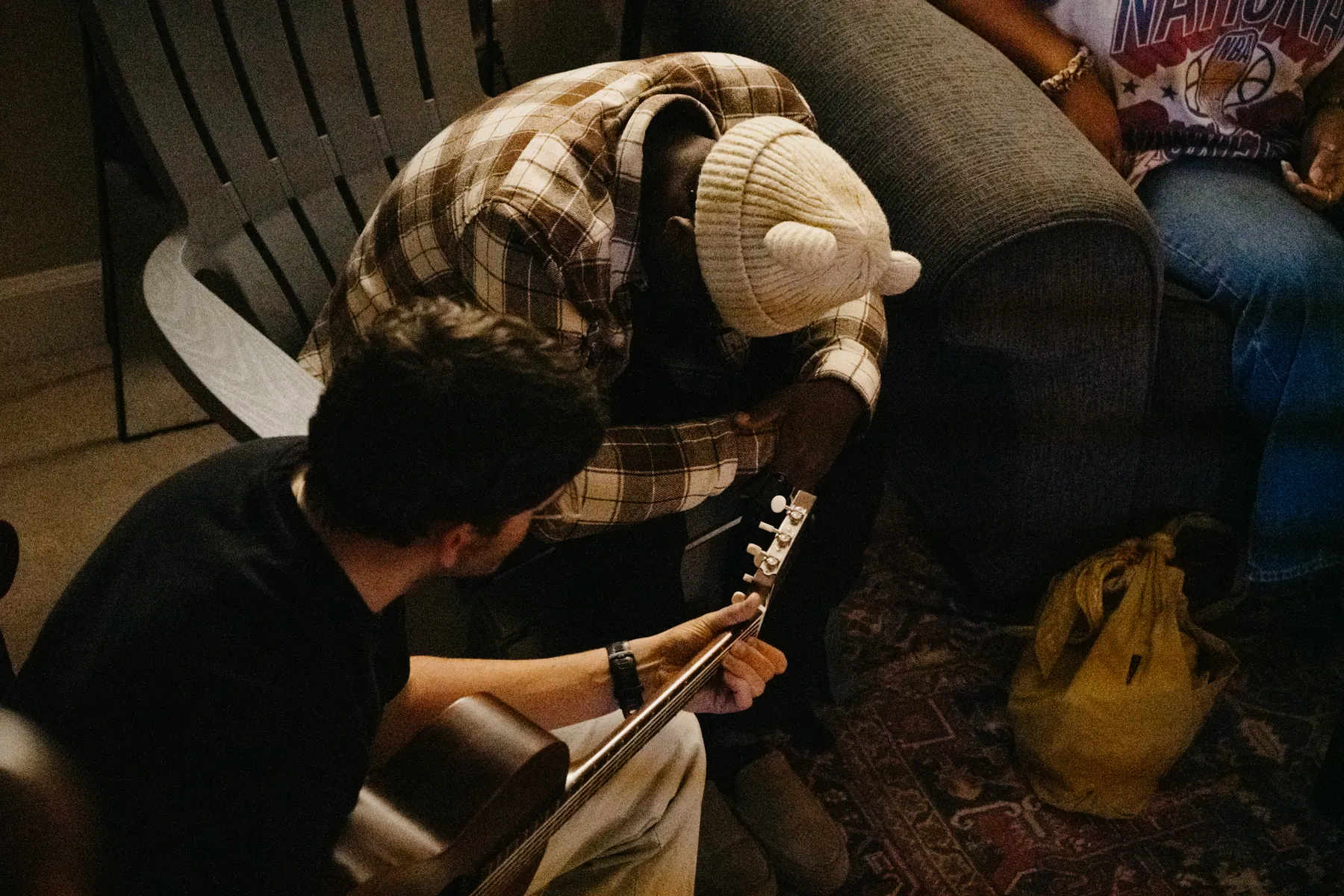 Two friends praying together, one still holding his guitar